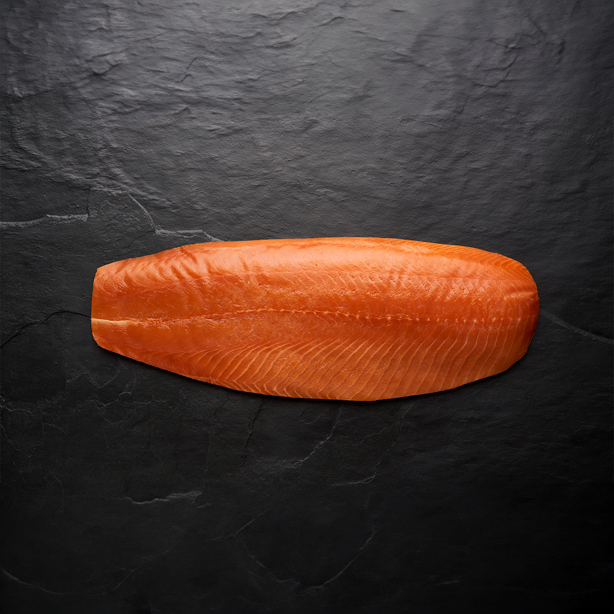 salmon fillet, photographed on a dark wooden surface.